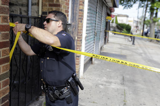 A police officer ties tape around the First American Fried Chicken restaurant, Wednesday, Sept. 21, 2016, in Elizabeth, N.J. The Elizabeth establishment and the apartment above are tied to Ahmad Khan Rahami, who was arrested as a suspect in the weekend bombings in New York and New Jersey. (AP Photo/Julio Cortez)