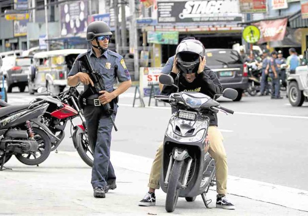 LAWMEN ROAM ‘LAWLESS’ LAND An officer manning a checkpoint on E. Rodriguez Avenue, Quezon City, orders  a motorcyclist to pull over for an inspection.  The police have been put on full alert after President Duterte declared a “state of lawless violence” in the wake of the Sept. 2 Davao City bombing. RICHARD REYES