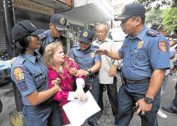ERMITA ARREST Marilou Balwart is secured by members of the Manila Police District led by Station 5 commander Supt. Albert Barrot (right) after she allegedly tried to fend off a court sheriff’s team with a “bang.”     MARIANNE BERMUDEZ