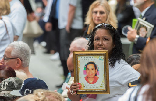 FILE- In this Sept. 11, 2015 file photo, a woman holds up a photograph during the ceremony commemorating the Sept. 11, 2001 terrorist attacks at the World Trade Center site in New York. Victims' relatives and dignitaries will once again convene Sunday, Sept. 11, 2016, on the memorial plaza at the World Trade Center for one of the constants in how America remembers 9/11 after 15 years, the anniversary ceremony itself. (AP Photo/Bryan R. Smith, File)