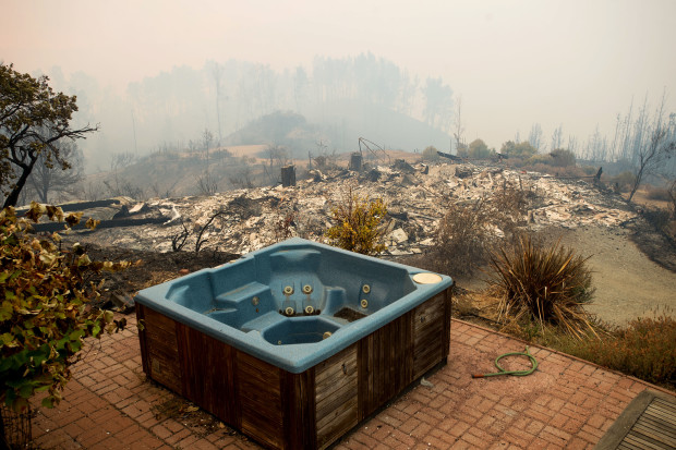 A hot tub rests in front of a residence leveled by the Loma fire along Loma Chiquita Road on Tuesday, Sept. 27, 2016, near Morgan Hill, Calif. More California residents were ordered from their homes Tuesday as a growing wildfire threatened remote communities in the Santa Cruz Mountains. (AP Photo/Noah Berger)