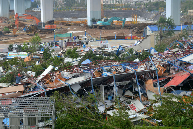 A man wearing a red helmet, left, climbs on the wreckage of a destroyed structure after a typhoon in Xiamen in southeastern China's Fujian province Thursday, Sept. 15, 2016. Typhoon Meranti, labeled the strongest storm so far this year by Chinese and Taiwanese weather authorities, made landfall in southeastern China early Thursday after previously affecting Taiwan. (Chinatopix via AP)