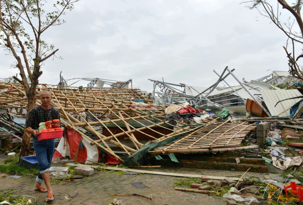 A man carries belongings away from a destroyed structure after a typhoon in Xiamen in southeastern China's Fujian province Thursday, Sept. 15, 2016. Typhoon Meranti, labeled the strongest storm so far this year by Chinese and Taiwanese weather authorities, made landfall in southeastern China early Thursday after previously affecting Taiwan. (Chinatopix via AP)