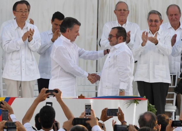 Colombian President Juan Manuel Santos (L) and the head of the FARC guerrilla Timoleon Jimenez, aka Timochenko, shake hands during the signing of the historic peace agreement between the Colombian government and the Revolutionary Armed Forces of Colombia (FARC), in Cartagena, Colombia, on September 26, 2016  Colombia will turn the page on a half-century conflict that has stained its modern history with blood when the FARC rebels and the government sign a peace deal on Monday. President Juan Manuel Santos and the leader of the FARC, Rodrigo Londono -- better known by his nom de guerre, Timoleon "Timochenko" Jimenez -- are set to sign the accord at 2200 GMT in a ceremony in the colorful colonial city of Cartagena on the Caribbean coast. / AFP PHOTO / Luis ACOSTA