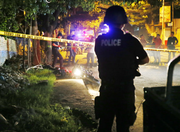 A police SWAT member stands guard as police operatives examine the scene where two bodies lay on a road after being killed in a police drug "buy-bust" operation before dawn Friday, Sept. 23, 2016 in Pasig city, east of Manila, Philippines. Philippine President Rodrigo Duterte said on Thursday he will invite the U.N. chief and European Union officials to investigate his bloody anti-drug crackdown, but only if he can question them in public afterward to prove their human rights concerns are baseless. More than 3,000 suspected drug dealers and users have been killed since July and more than 600,000 others have surrendered for fear of being killed in Duterte's crackdown. Despite growing alarm, Duterte said he won't stop the campaign.(AP Photo/Bullit Marquez)