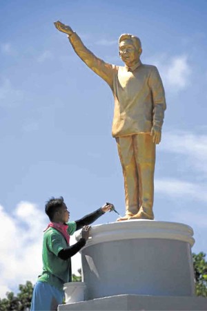 HAIL ‘APO’  A government worker cleans the statue of strongman Ferdinand Marcos in Sarrat town, Ilocos Norte province. EV ESPIRITU / Inquirer Northern Luzon