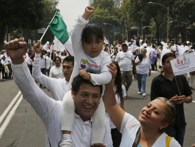 Demonstrators take part in a march organized by representatives of the National Front for the Family, in Mexico City, Saturday, Sept. 24, 2016. Dueling marches, in support and against Mexican President Enrique Pena Nieto’s push to legalize same-sex marriage, gathered at the Angel of Independence monument. The two sides were kept apart Saturday by hundreds of police and barriers erected around the city's iconic monument. (AP Photo/Marco Ugarte)