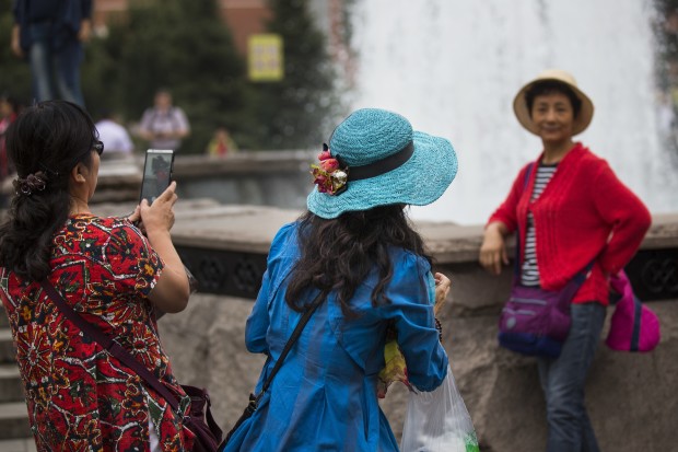 Chinese tourists make photos at a fountain just off Red Square in Moscow, Russia, Friday, Aug. 26, 2016. Warm weather has set in the Russian capital after a heatwave, with temperatures of around 24 C (75 F). (AP Photo/Alexander Zemlianichenko)