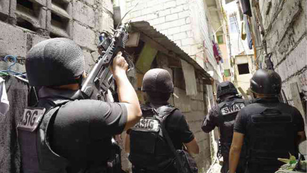BATTLE-READY Members of a Special Weapons and Tactics (SWAT) police team raid a house in a Pasig City slum to serve a search warrant as part of President Duterte’s deadly campaign against illegal drug trafficking.  AFP