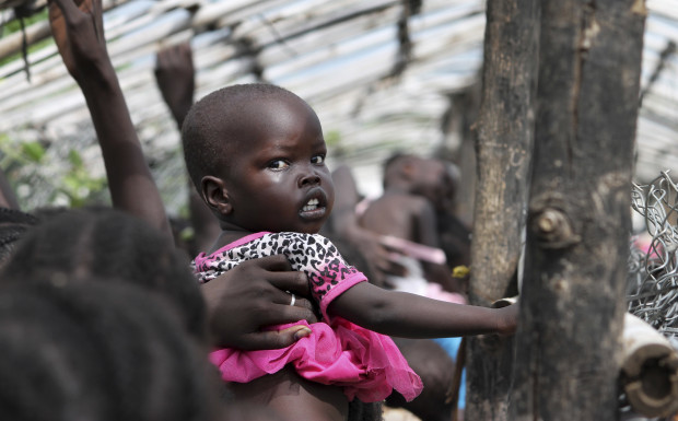 FILE - In this Monday, July 25, 2016 file photo, a baby is lifted up as people queue for food distribution in a camp for the displaced at the United Nations base in Juba, South Sudan. The United Nations said Friday, Sept. 9, 2016 that hunger in South Sudan has reached "unprecedented" levels, with nearly 5 million people suffering from severe food insecurity. (AP Photo/Justin Lynch, File)