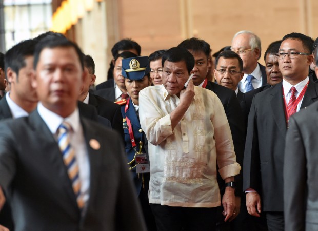 Philippine President Rodrigo Duterte wipes (C) his face while walking to the closing and handover ceremony for the Association of Southeast Asian Nations (ASEAN) Summit in Vientiane on September 8, 2016. US President Barack Obama urged Philippine leader Rodrigo Duterte on September 8 to conduct his crime war "the right way", after 3,000 people were killed in the crackdown in just over two months. / AFP PHOTO / ROSLAN RAHMAN