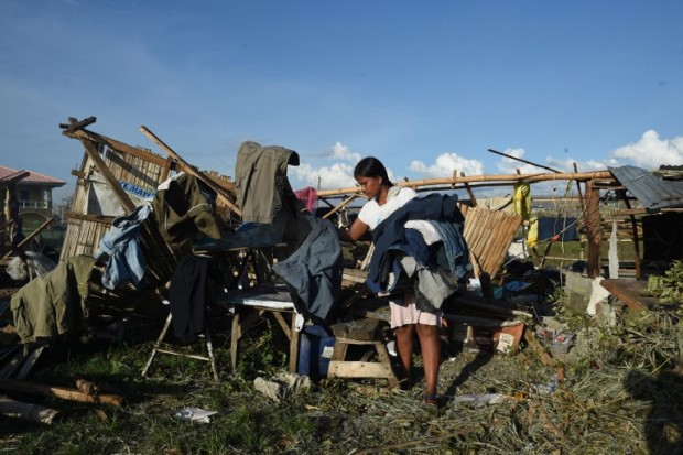 A resident removes dried clothes amongst the ruins of their house destroyed at the height of typhoon Haima in Cabagan town, Isabela province, north of Manila on October 21, 2016.  Hungry Philippine typhoon survivors huddled in makeshift shelters and waited for aid on October 21, after losing nearly everything from one of the most powerful storms to hit the Southeast Asian archipelago. / AFP PHOTO / TED ALJIBE