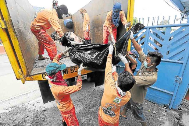 Workers load the decomposing bodies found at Henry Memorial Services funeral parlor on a dump truck for mass burial on Wednesday. —GRIG C. MONTEGRANDE