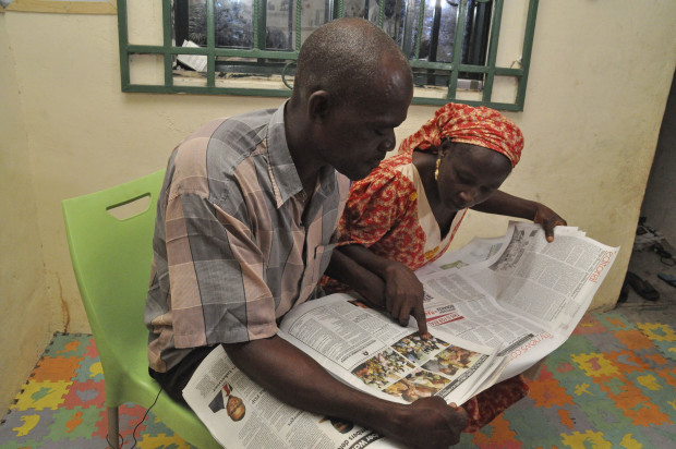 Abana Muta, left, and Hawa Abana, right, look at photos of the freed twenty-one Chibok schoolgirls in newspaper including their daughter Blessing Abana, in Nasarawa Nigeria, Saturday, Oct. 15, 2016. Conflicting reports emerged Friday about whether the first negotiated release of some Chibok schoolgirls kidnapped by Boko Haram in Nigeria in 2014 involved a ransom payment, a prisoner swap for Islamic extremist commanders, or both. ( AP Photo/Gbemiga Olamikan)