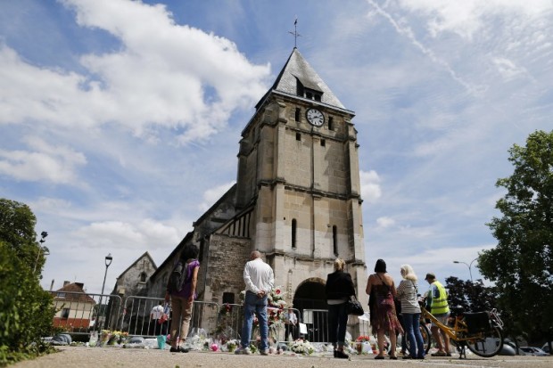 (FILES) This file photo taken on July 28, 2016 shows people gathering on July 28, 2016 near floral in front of the church of Saint-Etienne-du-Rouvray, northern France, where French priest Jacques Hamel was killed on July 26 in the church during a hostage-taking claimed by Islamic State group. / AFP PHOTO / CHARLY TRIBALLEAU