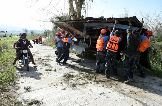 Policemen remove a roof, which was blown off its building by super typhoon Haima, along a road in a village in Penablanca town, Cagayan province, north of Manila on October 21, 2016.  Super typhoon Haima, one of the most powerful typhoons to ever hit the Philippines, killed at least eight people on October 20 as ferocious gales and landslides destroyed tens of thousands of homes. / AFP PHOTO / TED ALJIBE