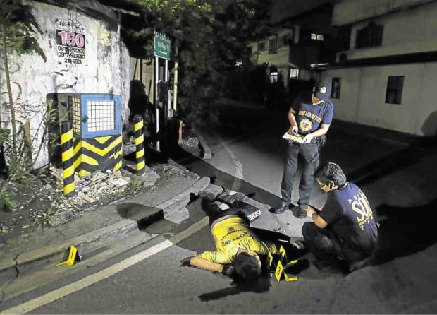 Police investigators inspect the body of alleged drug user Marcelo Salvador, who was shot by unidentified men near his home in Las Piñas City on Sept. 5.  AP PHOTOS