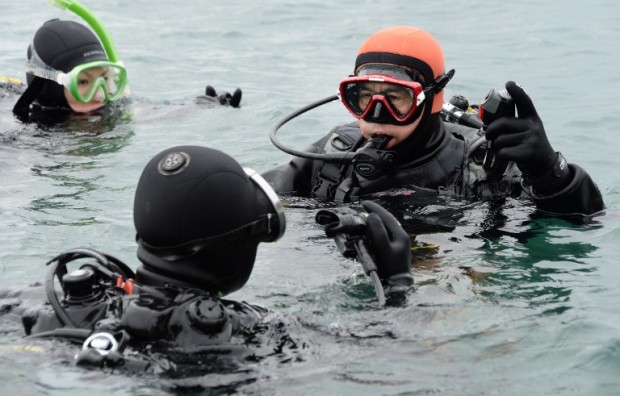 To go with story:  Japan-Nuclear-Disaster-Diving,FEATURE by Harumi Ozawa Yasuo Takamatsu (R) listens to his instructor in the ice-cold sea water in Onagawa, Miyagi Prefecture, on March 2, 2014.  Te 57-year-old bus driver started taking scuba diving lessons in November to find his wife who is still missing after the 3/11 tsunami.   AFP PHOTO/Toru YAMANAKA / AFP PHOTO / TORU YAMANAKA
