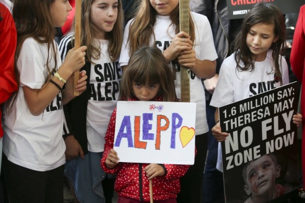 Children hold placards as they join a demonstration calling on the British government to take action to protect the children of the Syrian city of Aleppo outside Downing Street in central London on October 22, 2016.  Several campaign groups and charities including Avaaz and Amnesty International organised a rally outside Downing Street in London to call on the British government to set out a plan to protect Syrian children in the embattled Syrian city of Aleppo. Hundreds of wounded civilians were stranded in rebel-held areas of Syria's Aleppo on October 22 after the UN said security concerns had prevented evacuation convoys even as Russia extended a ceasefire into a third day. / AFP PHOTO / Daniel Leal-Olivas