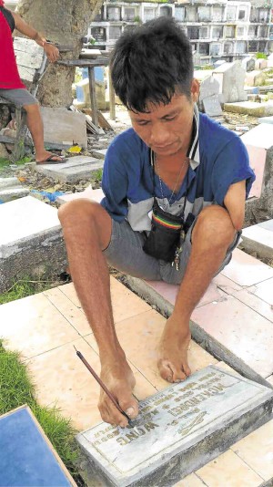  Vicente Dahunan paints a tomb using his feet at the public cemetery of Mandaue City. —CARINE ASUTILLA-LAPID