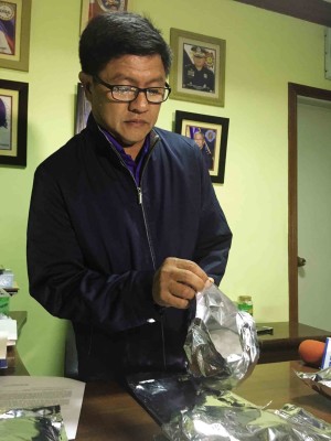 Senior Supt. Rodolfo Recomono Jr., Pampanga police chief, opens one of 10 aluminum packs surrendered on Oct. 13 by an inmate in New Bilibid Prison.—TONETTE T. OREJAS