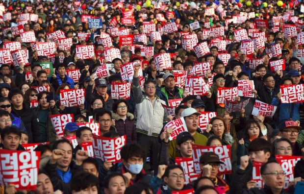 Tens of thousands of protesters hold up signs calling for the resignation of South Korean President Park Geun-Hye during an anti-government rally following presidential scandal in central Seoul on November 12, 2016. Tens of thousands of men, women and children joined one of the largest anti-government protests seen in Seoul for decades on November 12, demanding President Park Geun-Hye's resignation over a snowballing corruption scandal. / AFP PHOTO / JUNG YEON-JE