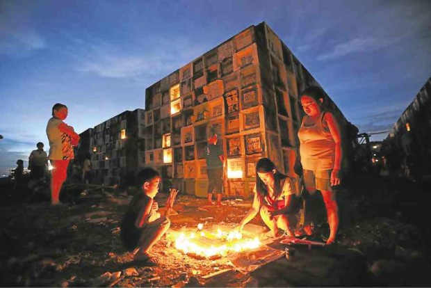 CEMETERY VIGIL Illuminated only by candles, families start an overnight vigil near the place where their departed loved ones are buried on the eve of All Saints’ Day at Navotas City Public Cemetery. —RAFFY LERMA
