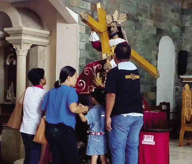 A family prays before the replica of the Black Nazarene of Quiapo at Saint Joseph parish church in Tacloban City. —JOEY GABIETA
