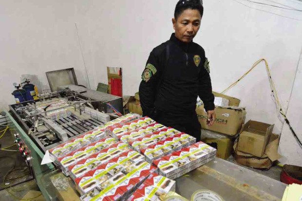 A policeman inspects packs of fake cigarettes seized from a factory in Villasis town  in Pangasinan province.  —RAY ZAMBRANO 