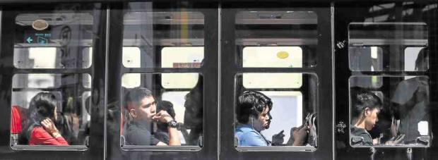 Bus passengers use their gadgets to take their mind off the slow-moving traffic on Edsa. —LYN RILLON