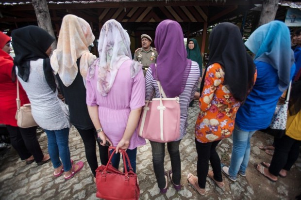 An Indonesian Muslim official (C-brown uniform) speaks to female students caught wearing tight trousers which is against shariah-law in Banda Aceh on September 3, 2013. Aceh is the only province in Indonesia to implement sharia law where Muslim women are obliged to wear Muslim clothes, covering their hair with veils and no tight trousers. AFP PHOTO / CHAIDEER MAHYUDDIN / AFP PHOTO / CHAIDEER MAHYUDDIN