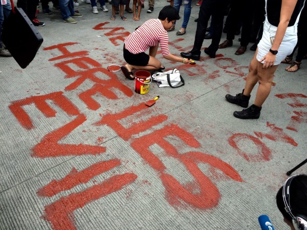 An anti-Marcos protester paints "Here lies evil," just 200 meters away from the gates of the Libingan ng mga Bayani. Photo by Lyn Rillon/INQUIRER
