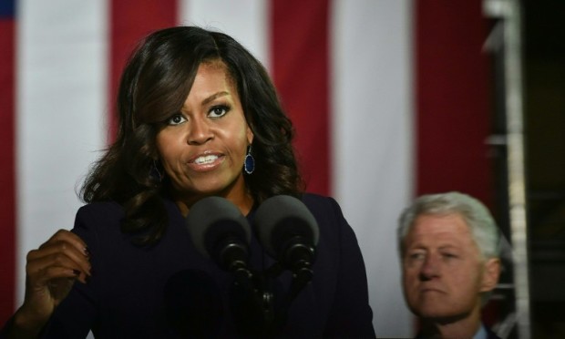 US First Lady Michelle Obama (L) adresses the crowd as US former President Bill Clinton looks on during a rally for Democratic presidential nominee Hillary Clinton, on Independence Mall, November 7, 2016 in Philadelphia, Pennsylvania. About 40,000 people flooded Independence Mall in Philadelphia for Hillary Clinton's rally with her husband Bill, President Barack Obama and his wife Michelle at her side, a campaign aide said. The attendance set a new record for Clinton, with the previous high point a rally in Ohio that drew 18,500 people, a campaign aide told reporters traveling with the candidate.  / AFP PHOTO / NICHOLAS KAMM