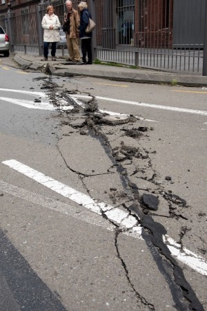 Members of the public inspect the damage to the road on the Wellington water front after a 7.8 earthquake centred in the South Island, in Wellington on November 14, 2016.  Rescuers in New Zealand were scrambling Monday to reach the epicentre of a powerful 7.8 earthquake that killed at least two people and sparked a tsunami alert that sent thousands fleeing for higher ground. / AFP PHOTO / Marty Melville