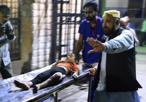 Pakistani rescuers transport an injured boy to a hospital in Karachi on November 12, 2016, following a suicide bombing at a Sufi shrine. At least 52 people died and more than 100 others were injured November 12 in a bomb blast at a remote Sufi shrine in Pakistan, officials said, with the Islamic State group claiming the attack. The blast hit worshippers participating in a ceremony at the shrine of the Sufi saint Shah Noorani, some 750 kilometres (460 miles) south of Quetta, the provincial capital of restive southern Balochistan province.  / AFP PHOTO / RIZWAN TABASSUM