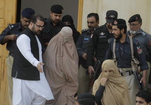 Pakistani officials escort famed Afghan woman Sharbat Gulla in a burqa or veil outside a court in Peshawar, Pakistan, Friday, Nov. 4, 2016. A prosecutor says Pakistani court has ordered two weeks jail term and deportation for National Geographic's famed green-eyed 'Afghan Girl,' over allegedly forged ID papers and illegal stay in the country. Mohsin Dawar said Friday Sharbat Gulla pleaded guilty to the federal investigator's charges. (AP Photo/Mohammad Sajjad)