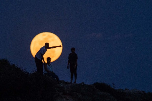 People watch the supermoon rising in Dar es Salaam on November 14, 2016. The moon will be the closest to Earth since 1948 at a distance of 356,509 kilometres (221,524 miles), creating what NASA described as "an extra-supermoon". / AFP PHOTO / DANIEL HAYDUK