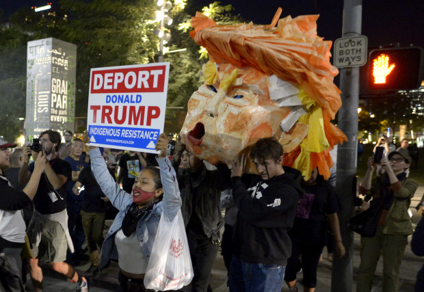 Protesters carry a paper head of President-elect Donald Trump during a protest in front of City Hall Wednesday, Nov. 9, 2016 in Los Angeles. A day after  Trumps election as president, the divisions he exposed only showed signs of widening as many thousands of protesters flooded streets across the country to condemn him.  (Keith Birmingham/The Pasadena Star-News/SCNG via AP)