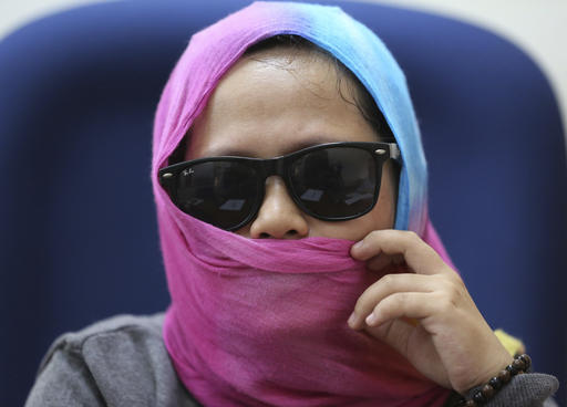 In this Sept. 7 photo, Harra Kazuo, live-in partner of alleged drug pusher Jaypee Bertes, covers her face to protect her identity during an interview at the Commission on Human Rights office in Quezon City, north of Manila, Philippines. Bertes was allegedly shot to death by police with his father-in-law following a drug raid which is part of the continuing anti-drugs campaign of Philippine President Rodrigo Duterte. The Commission on Human Rights has feared for her safety while it probes her case and has put her under an extraordinary witness protection program. (AP Photo/Aaron Favila)