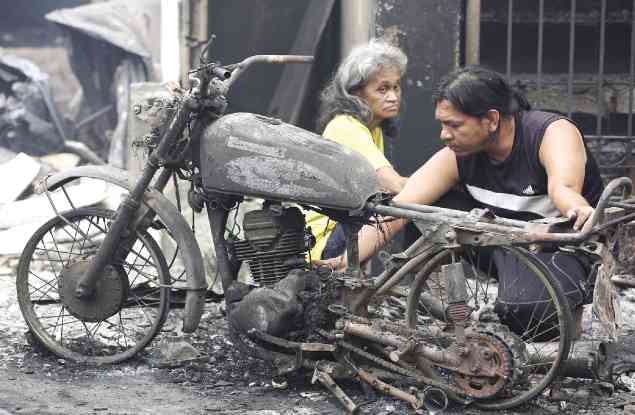 Like survivors in a war zone, residents of Welfareville Compound in Barangay Addition Hills survey the damage after a blaze hit the fire-prone area on Sunday. —NIÑO JESUS ORBETA