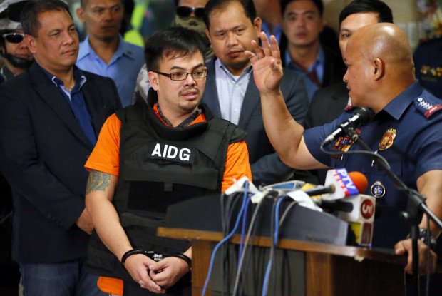 Alleged Filipino drug lord Kerwin Espinosa, center, listens to Philippine National Police Chief Gen. Ronald "Bato" Dela Rosa, right, as he is presented to the media upon arrival from Abu Dhabi early Friday, Nov. 18, 2016 at Camp Crame in suburban Quezon city, northeast of Manila, Philippines. Espinosa, whose father Mayor Rolando Espinosa was killed inside his detention cell, told a news conference he will "tell all" those involved in the illegal drug trade in the country. (AP Photo/Bullit Marquez)
