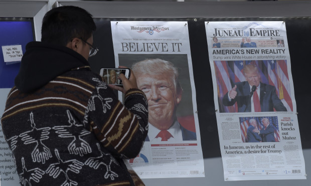 Zheng Gao of Shanghi, China, photographs the front pages of newspapers on display outside the Newseum in Washington, Wednesday, Nov., 9, 2016, the day after Donald Trump won the presidency. AP