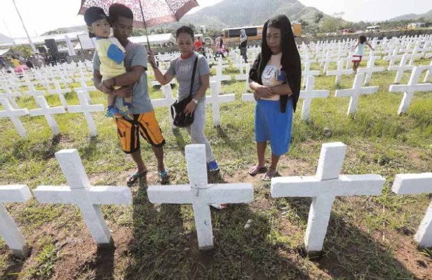 MASS GRAVE Survivors of Supertyphoon “Yolanda” remember their loved ones who perished in the tragedy three years ago during a visit to amass grave at Holy CrossMemorial in Barangay Basoar, Tacloban City. —JOAN BONDOC