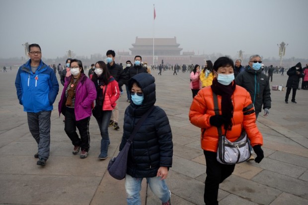 A group of people wearing masks visit Tiananmen Square in Beijing on December 21, 2016.  Beijing issued its first air pollution red alert for 2016 on December 15, with choking smog expected to cover the city and surrounding areas in north China until December 21. / AFP PHOTO / WANG ZHAO