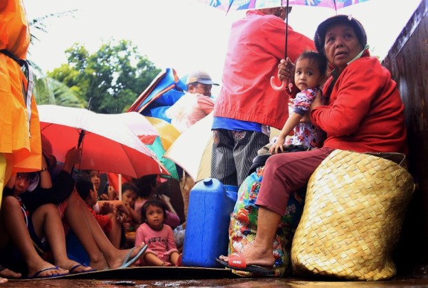 Residents sit in a truck after the local government implemented preemptive evacuations at Barangay Matnog, Daraga, Albay province on December 25, 2016, due to the approaching typhoon Nock-Ten.  Babies, toddlers and old people were loaded onto military trucks in the Philippines on December 25 as thousands fled from the path of a powerful typhoon barrelling towards the disaster-prone archipelago.  / AFP PHOTO
