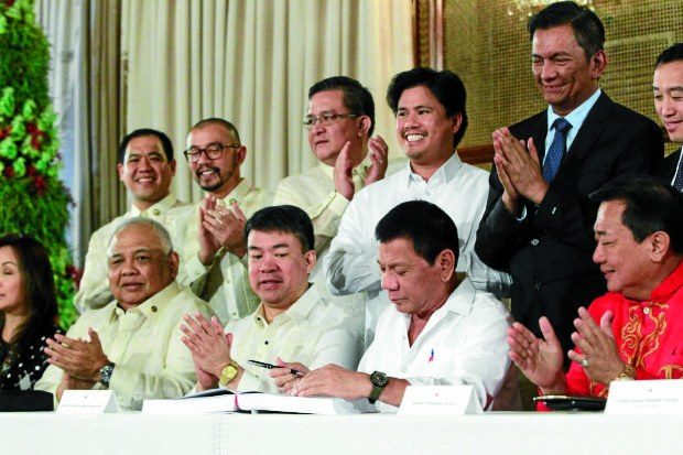 APPROVED President Duterte, flanked by Senate President Aquilino Pimentel III and Speaker Pantaleon Alvarez, signs Republic ActNo. 10924, or the 2017 General Appropriations Act, on Thursday as lawmakers give him a big round of applause at Rizal Hall in Malacañang. —MALACAÑANGPHOTO