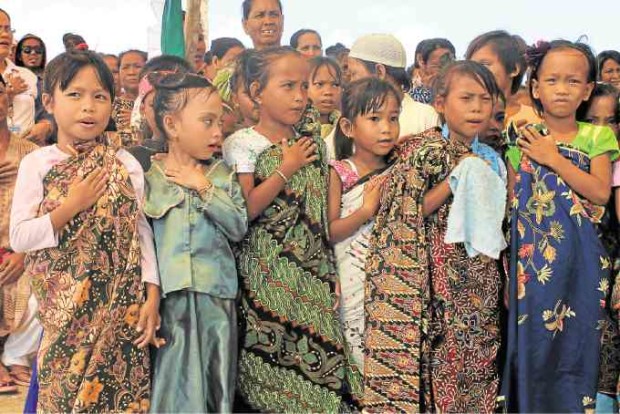 Bajau girls sing the Philippine national anthem during the launch of their boat classroom.