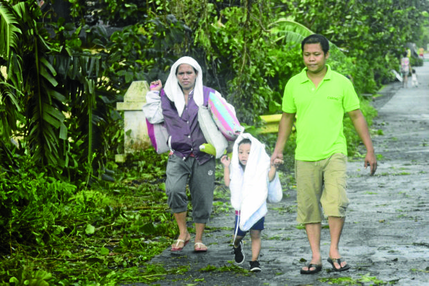 LONG WALK A family heads for home in Barangay San Joaquin, Legazpi City, on Monday, after spending Christmas in an evacuation center as powerful Typhoon “Nina” blew away from Bicol. —SHAN GABRIEL APULI