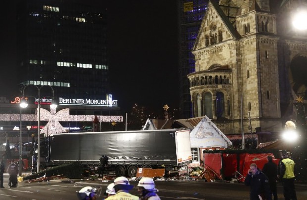 Policemen stand next to a truck that crashed into a christmas market in Berlin, on December 19, 2016 killing at least one person and injuring at least 50 people. Ambulances and police rushed to the scene after the driver drove up the pavement of the market in a central square popular with tourists less than a week before Christmas, in a scene reminiscent of the deadly truck attack in Nice. / AFP PHOTO / Odd ANDERSEN