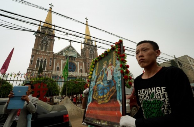 Catholics carry a portrait of the Virgin Mary at the start of a religious parade from the Catholic cathedral in Donglu, Hebei Province on May 26, 2013.  Police surrounded a Chinese village to prevent pilgrims from joining a Catholic parade to honour the Virgin Mary, who locals say appeared in the village a century ago.    AFP PHOTO / Mark RALSTON / AFP PHOTO / MARK RALSTON